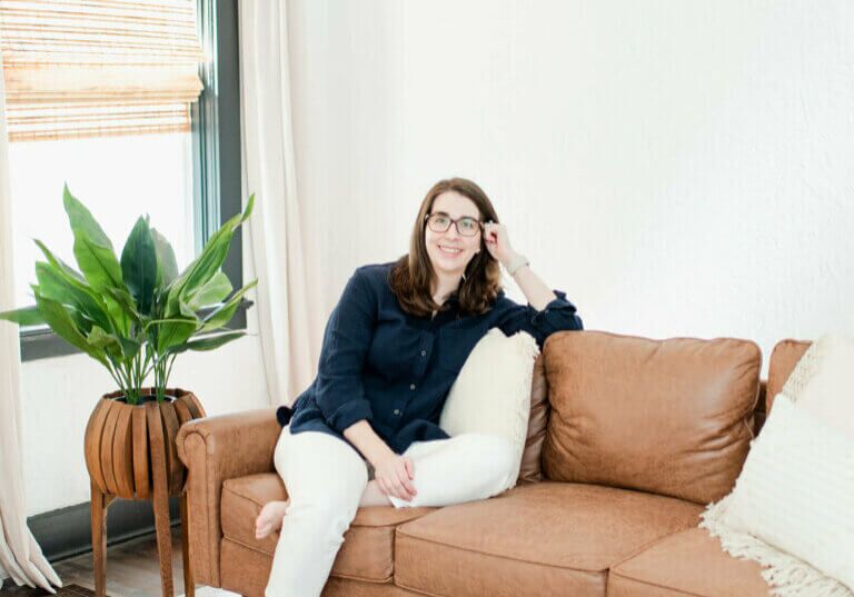 Lauren Scheffer Travel Agent for Families with Food Allergies sitting on leather sofa in Travel Accommodations With Food Allergies.